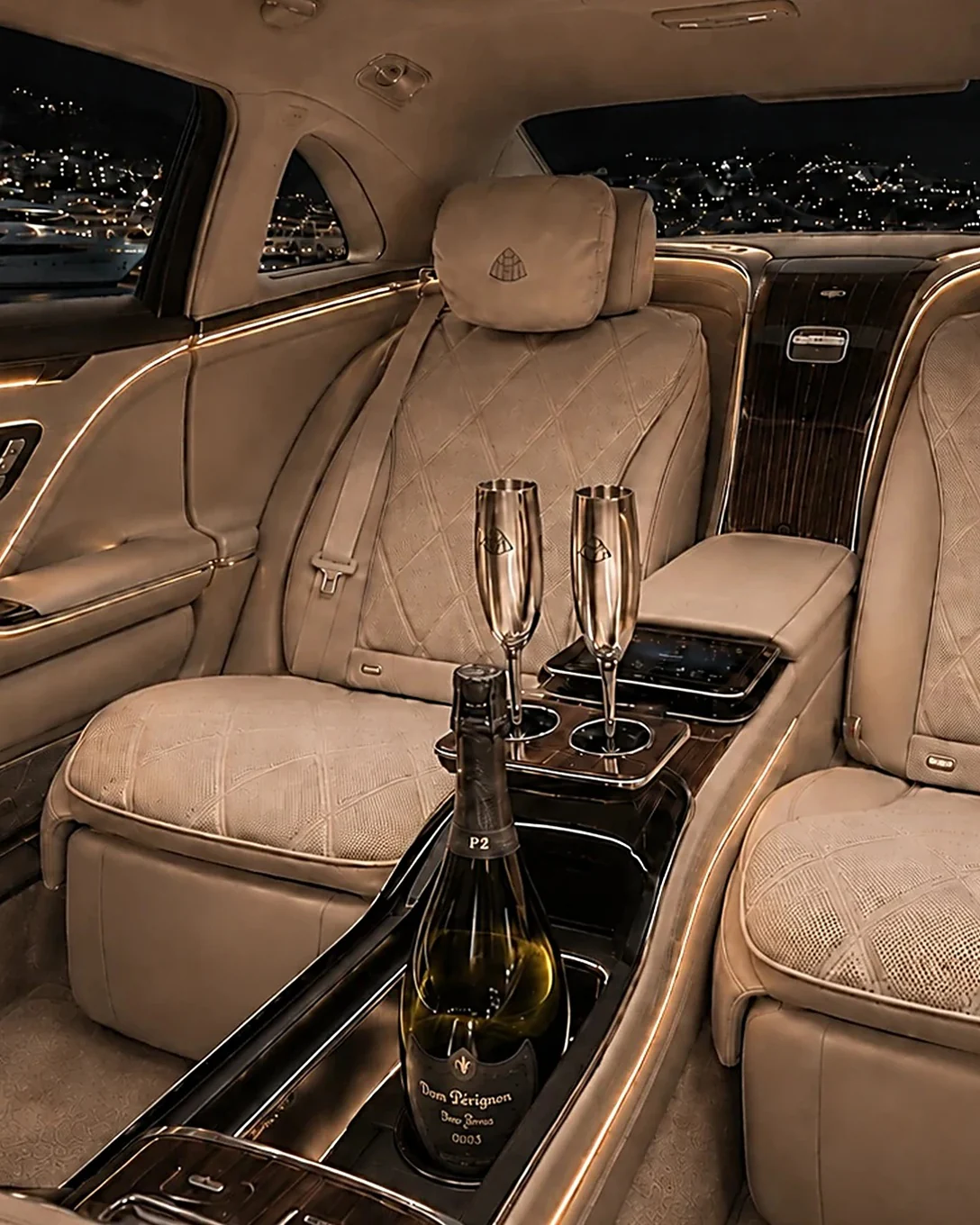 Rear cabin of a Mercedes-Benz with two champagne flutes and a chilled bottle, ready for a private chauffeur service on the French Riviera